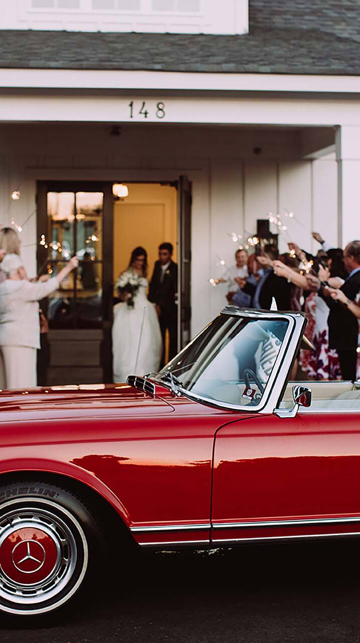 Wedding couple walking towards a red car